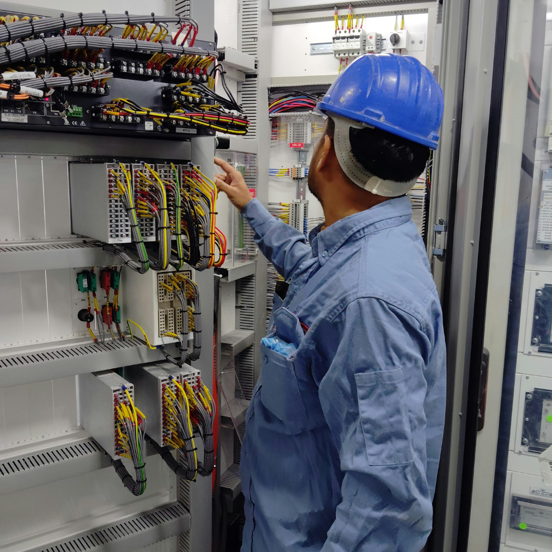 Electricista trabajando en panel eléctrico con casco azul