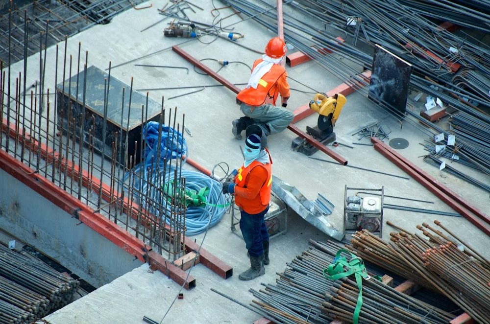 Dos trabajadores con cascos amarillos revisando planos de construcción